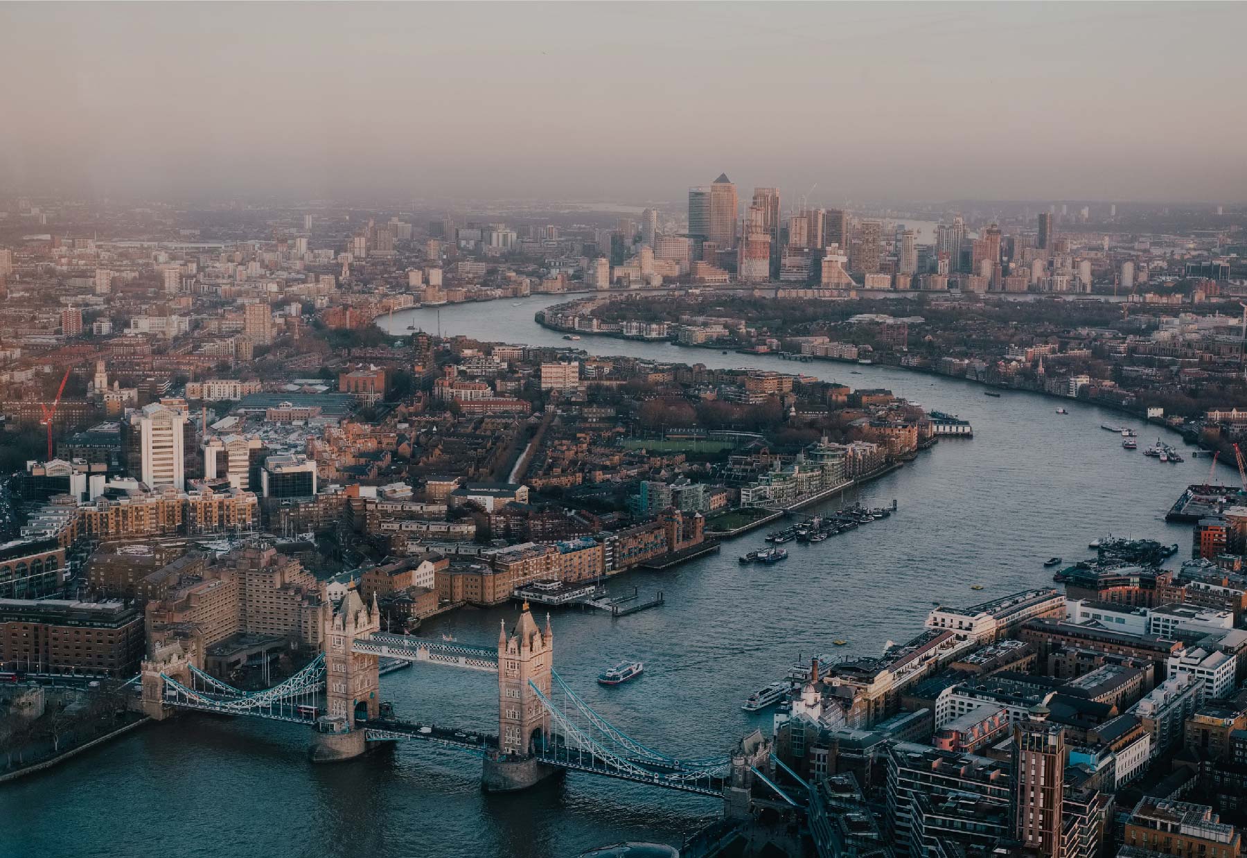 Aerial view of the River Thames winding through the city of London. City skyline with the Tower Bridge in the forefront.
