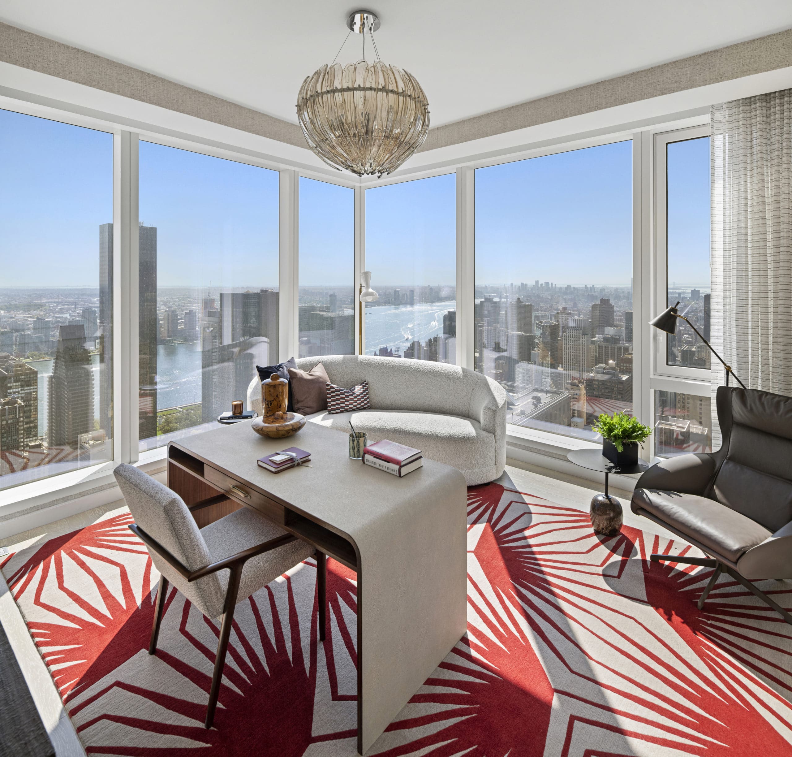 Corner living room in The Centrale in New York. A desk and couch in front of floor-to-ceiling windows overlooking the city.