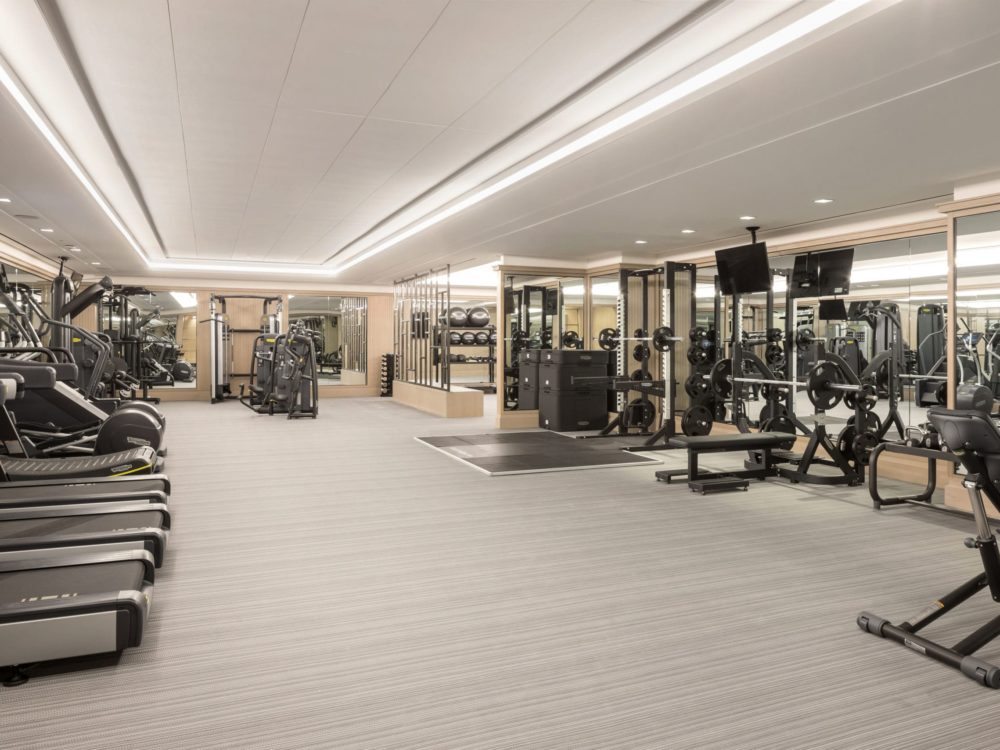 Fitness center at The Kent luxury condos in New York. Mirrored walls & carpet floors with free weights and cardio equipment.