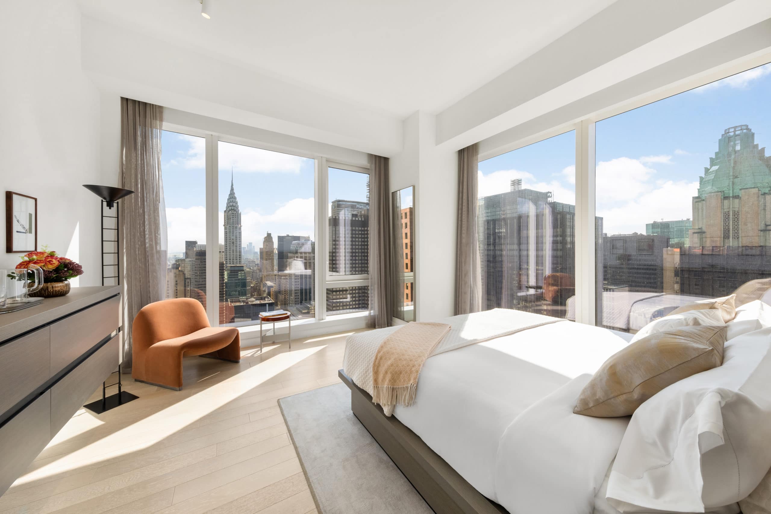 Bedroom at The Centrale condos in New York City. Corner bedroom with a bed, dresser, and large windows with city views.