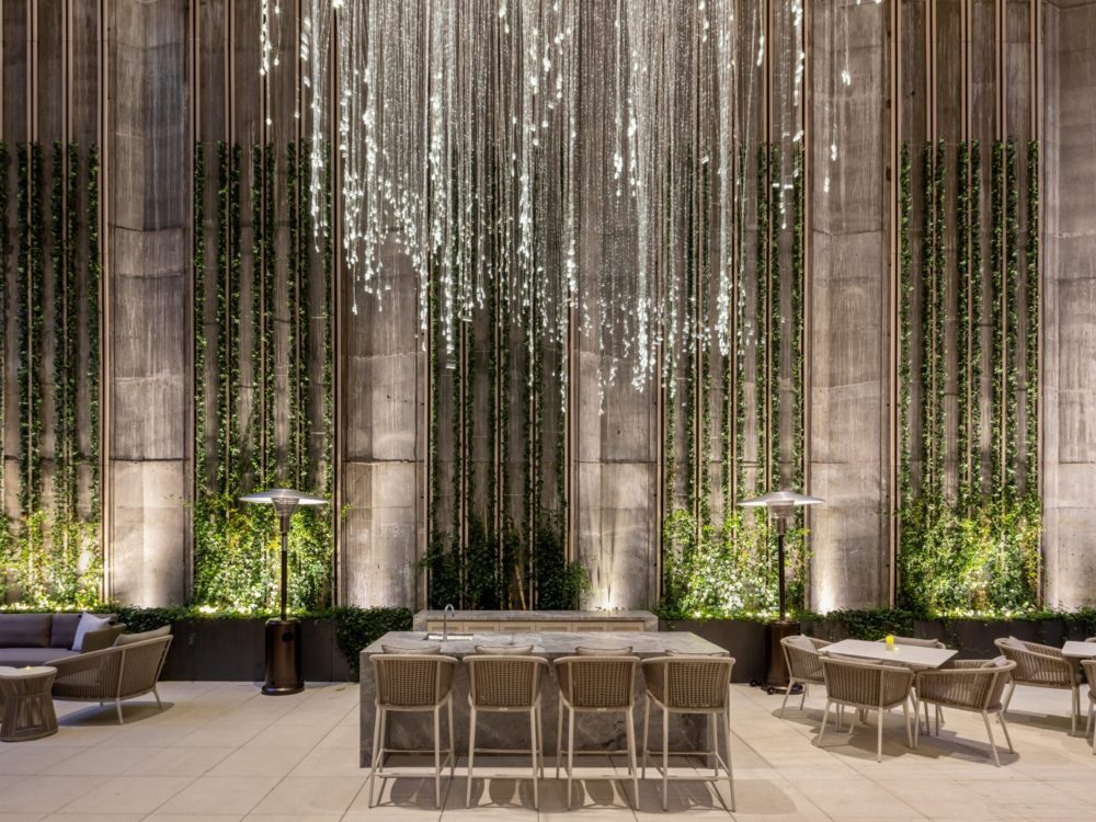 Outdoor space for residents at The Centrale in NYC. Hanging glass art chandelier above seating area and bordering planters.