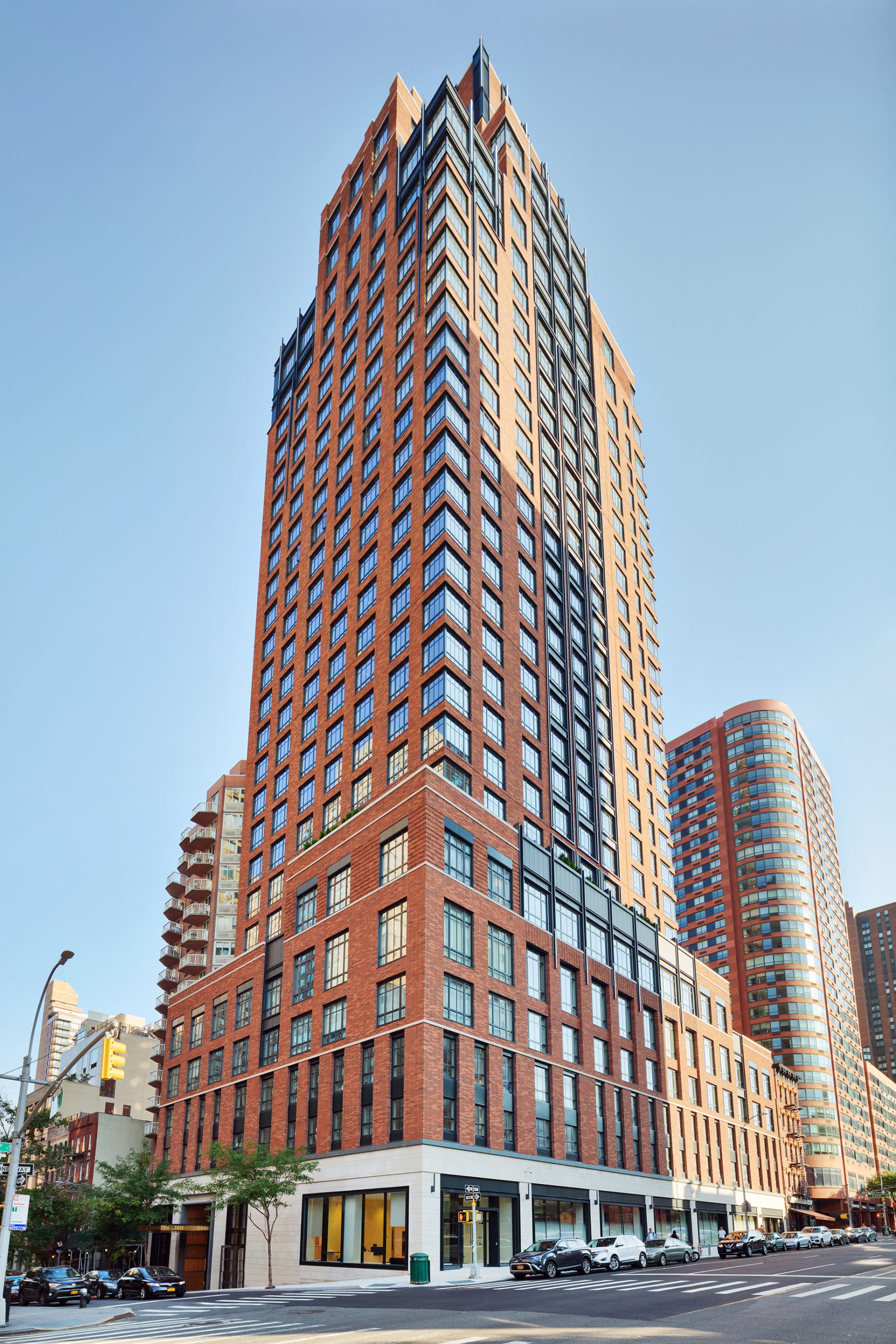 Exterior view of The Kent condominiums in New York. Street level view looking up at the brick high rise during daytime.