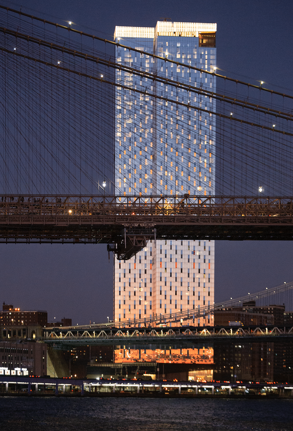 Night-time river view of One Manhattan Square luxury condominiums in New York City. Lit high rise in the starry night sky.