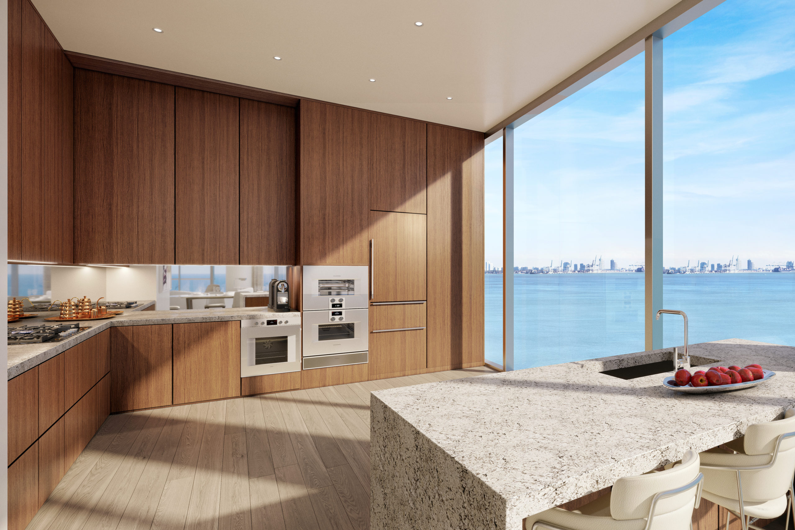 Kitchen with view at Una Residences in Miami. Open kitchen with large island, stone countertops, and wood built-in cabinets.