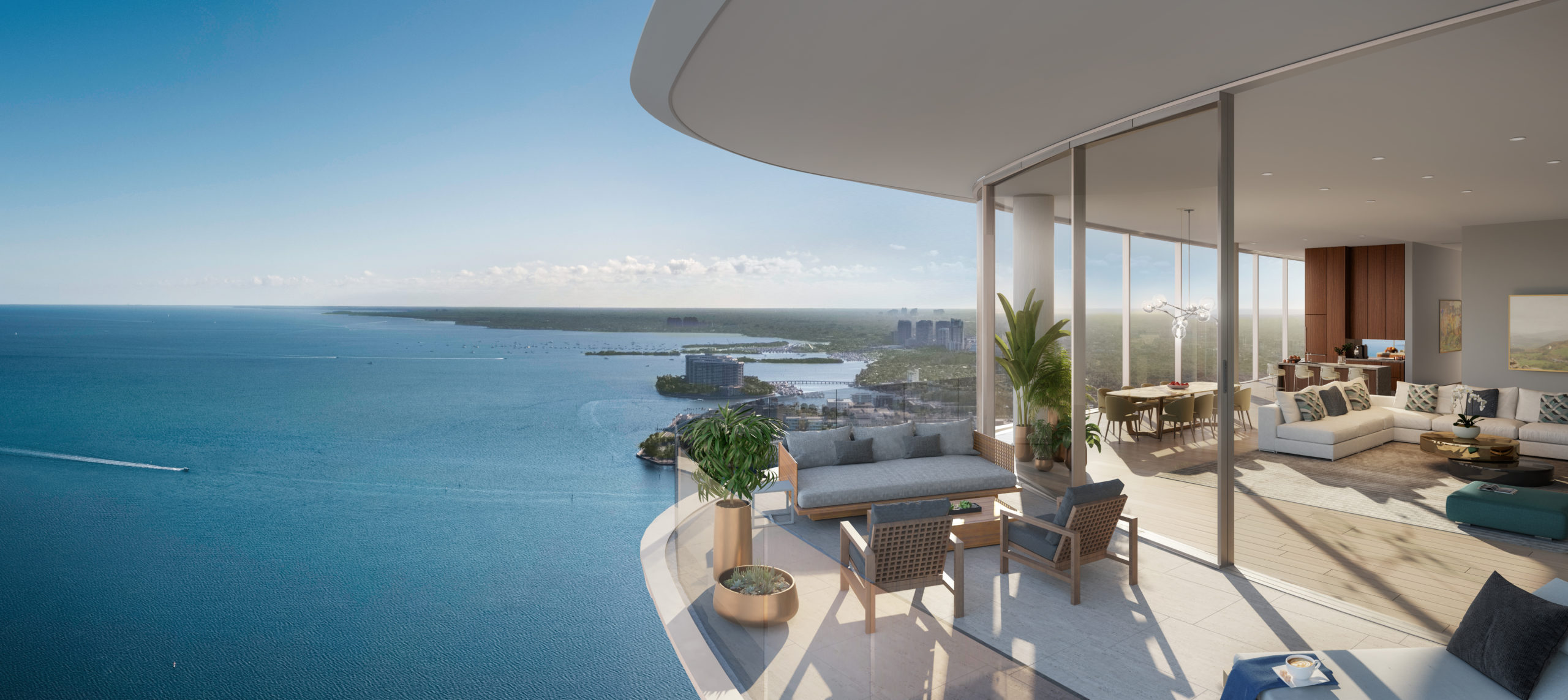 Exterior view of balcony overlooking the bay at Una Residences in Miami. Covered balcony with seating and potted plants.