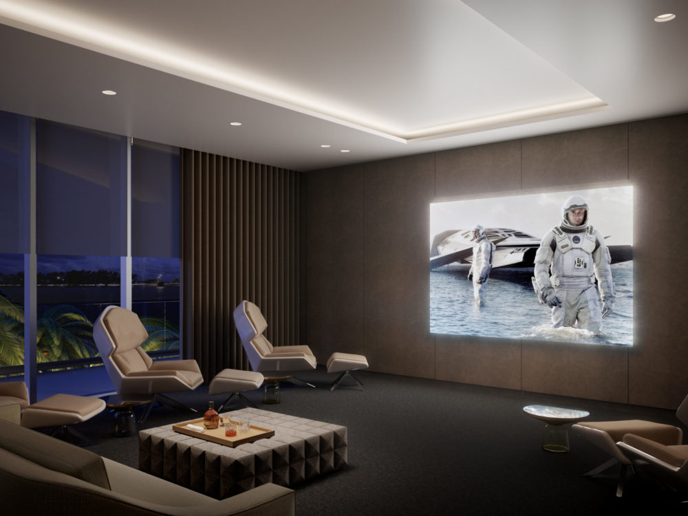 Cinema style media room at Una Residences in Miami with mounted projector, chairs and a couch, and blackout curtains.