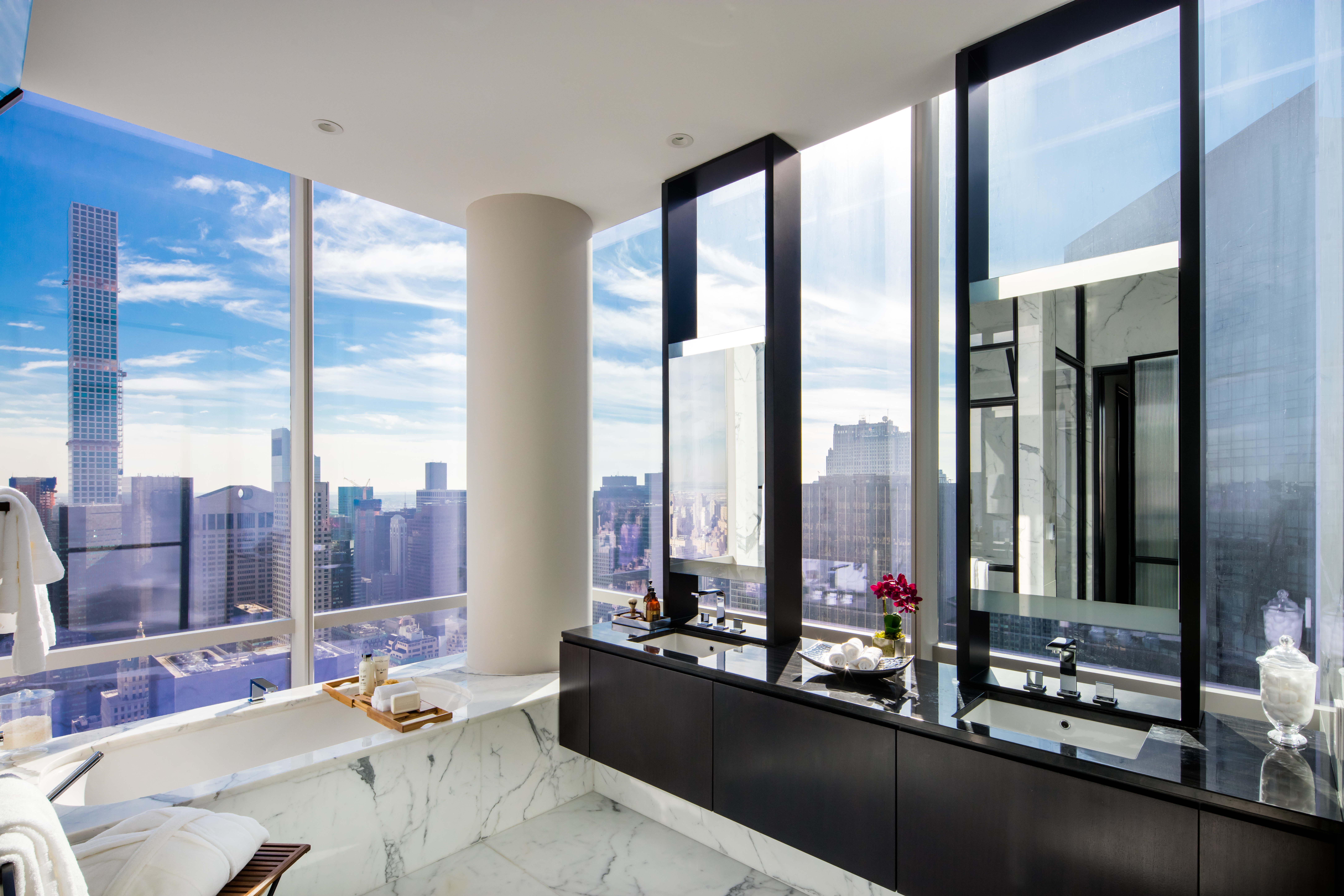 Bathroom at One 57 condos in New York. Marble floors, dark wood double vanity and floor-to-ceilings windows with city views.