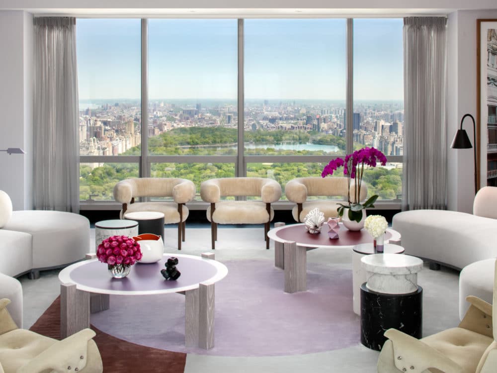 Living room at One 57 condominiums in New York. Light colored furniture, two coffee tables and floor-to-ceilings windows.