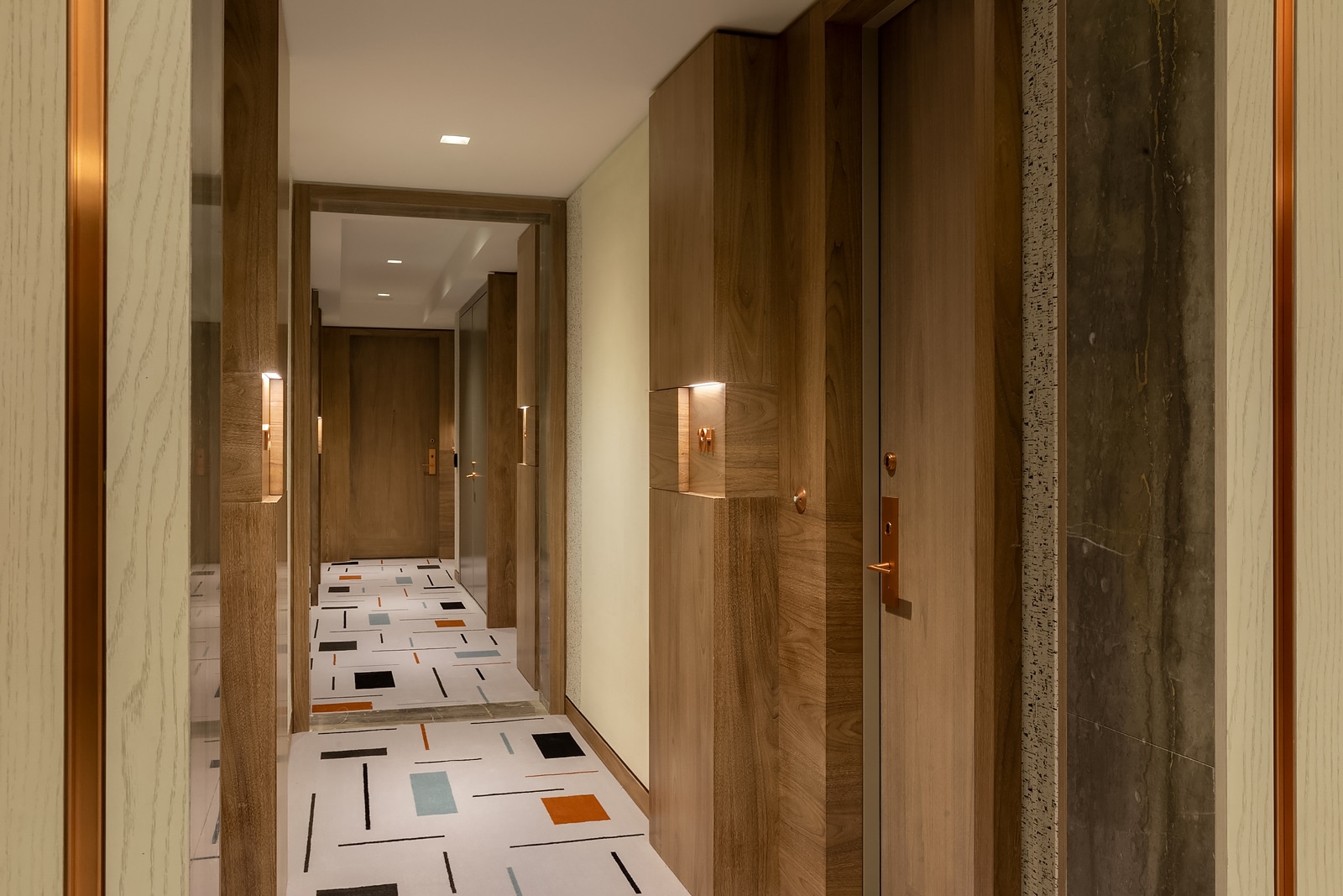 Interior view of Brooklyn Point condominiums hallway. Has patterned floors, beige walls and wooden door frames.