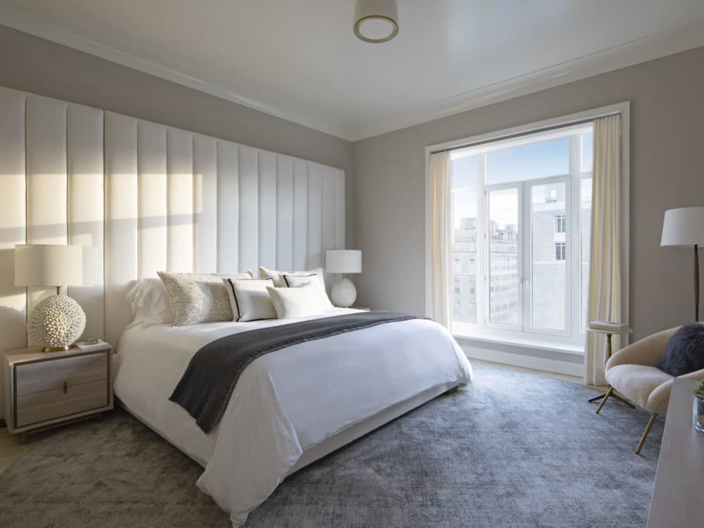 Interior view of 40 East End Ave residence master bedroom with window view of NYC. Has beige walls and white bed.