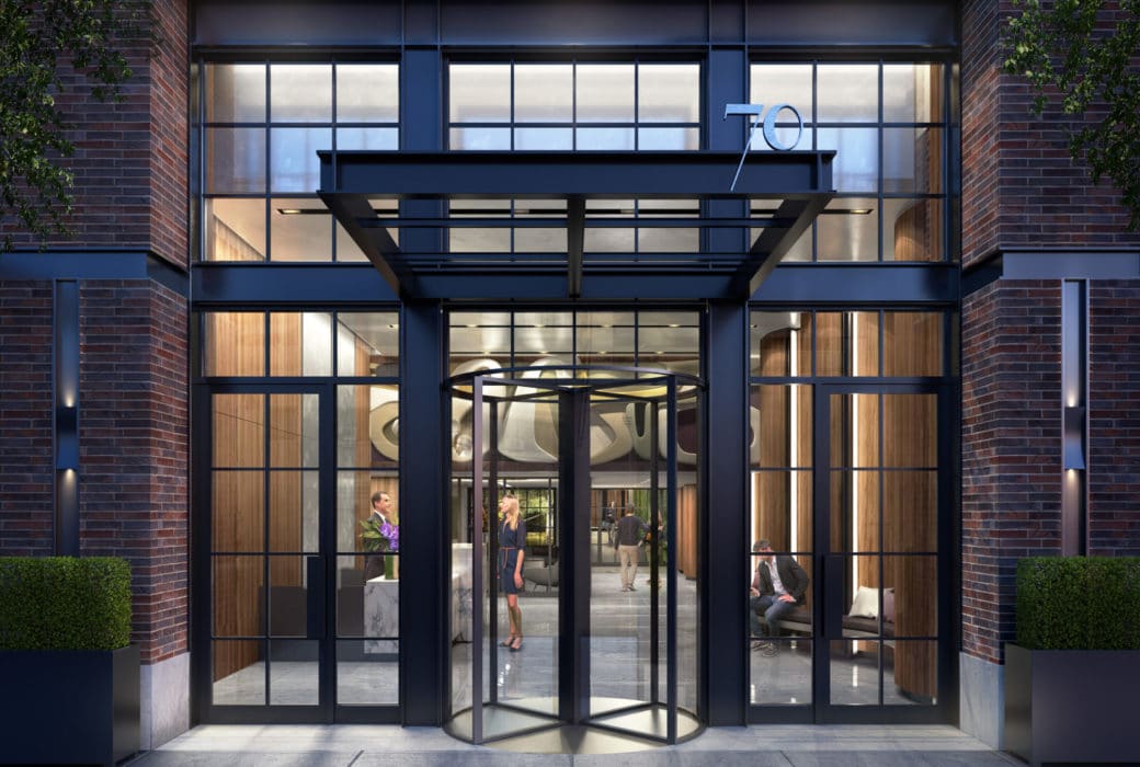 Exterior view of the entrance to 70 Charlton condominiums lobby in New York City. Has black framed windows and rotating door.