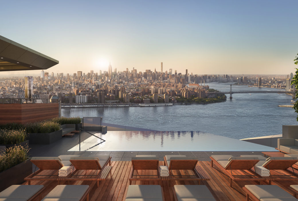 Exterior view of Brooklyn Point condominiums outdoor pool with river view and red lounging chairs in New York City.