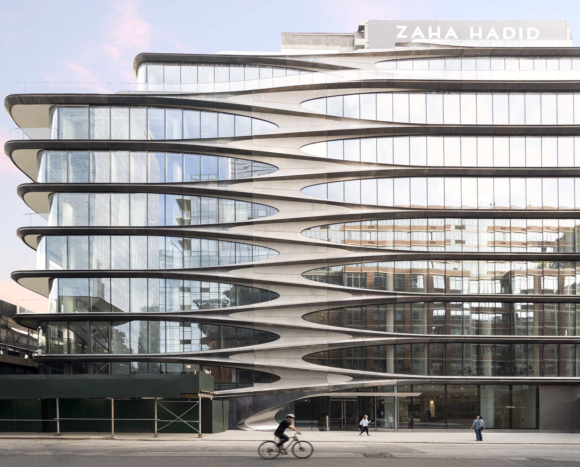 Ground view of 520 W 28 condominiums in New York City. Has view of a cyclist riding in the street.