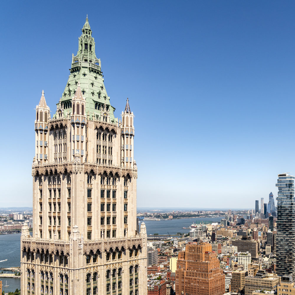 Birdseye view of the Woolworth Tower penthouse in New York. Downtown skyline of NYC in the background with blue skies.
