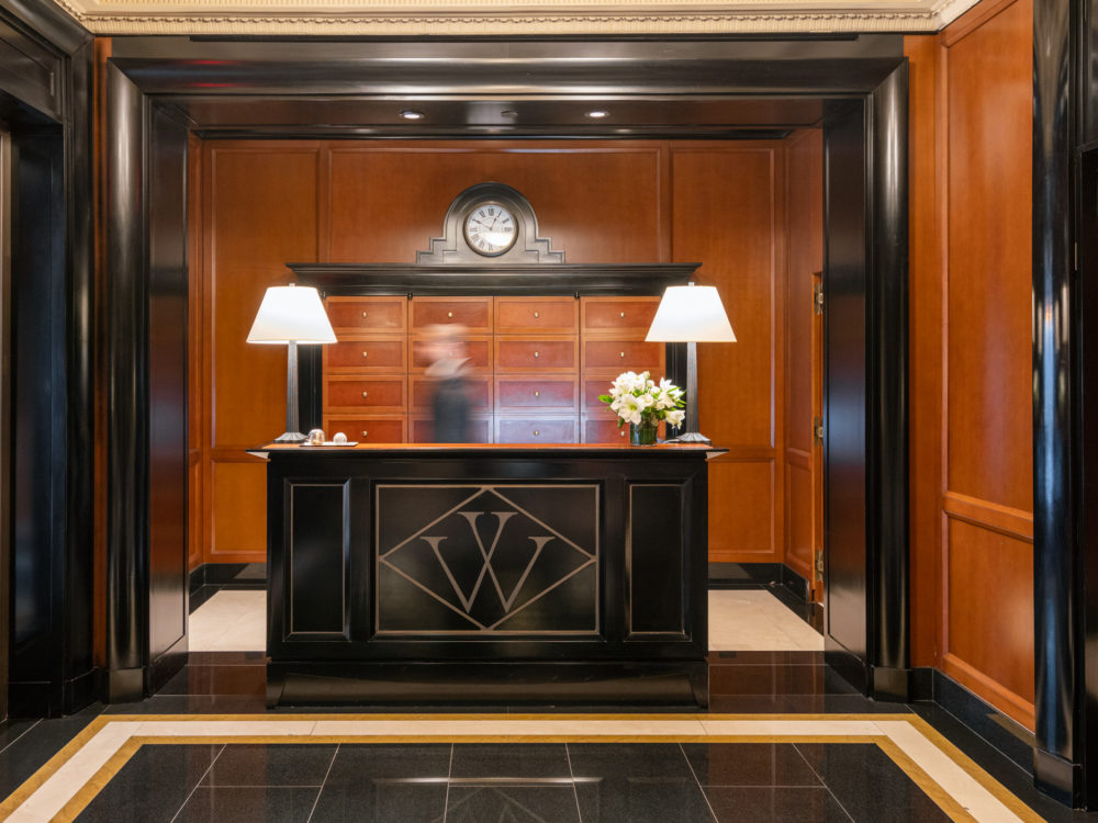 Front lobby at the Woolworth Tower luxury condos in New York. Dark wood walls with black finishings and a black front desk.