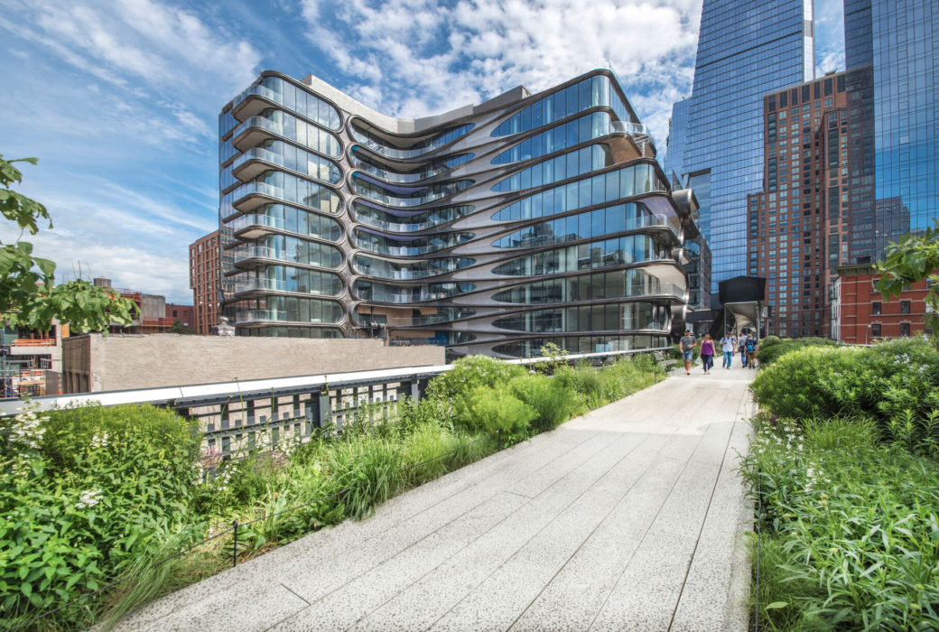 Ground view of 520 W 28 condominiums in New York City. Has a pathway leading into buildings with green shrubbery on side.