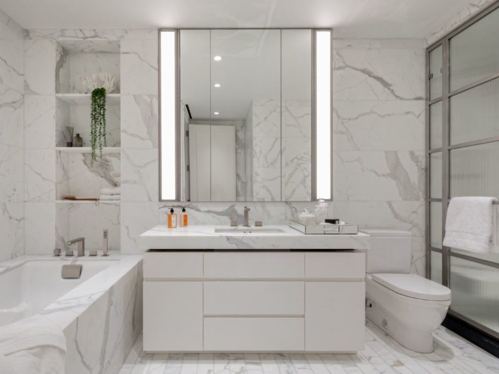Interior view of 70 Vestry residence bathroom in New York City. Has marble floors, walls and bathtub.