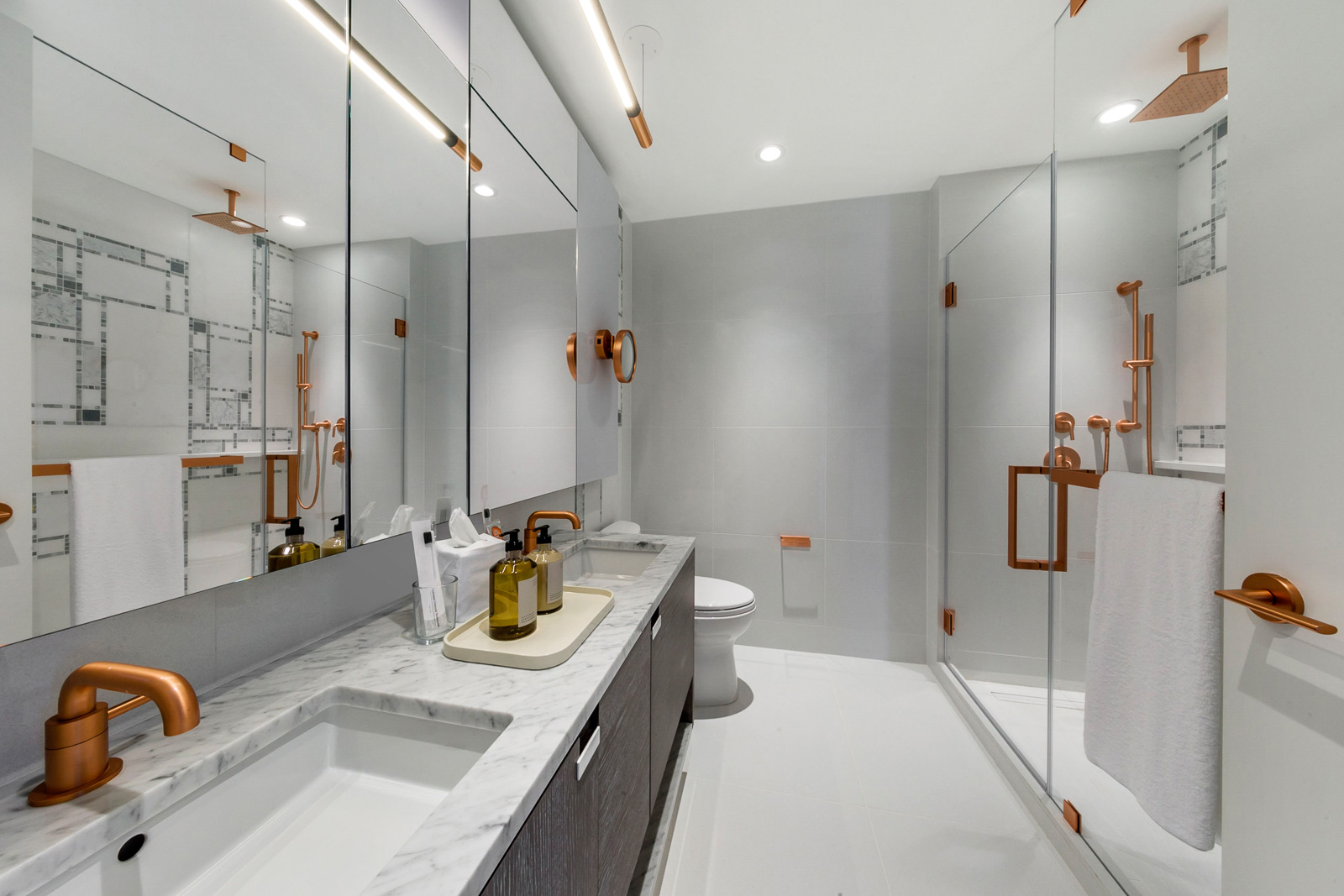 Interior view of Brooklyn Point residence master bathroom. Has marble counters and showers with gold trim.