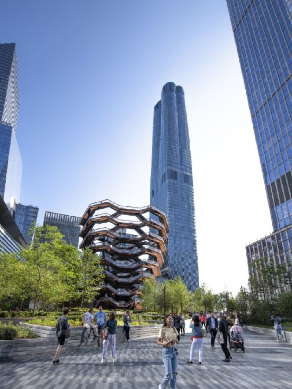 Ground view of 15 Hudson Yards condominiums in New York City. Includes glass walkway structure and people in the street.