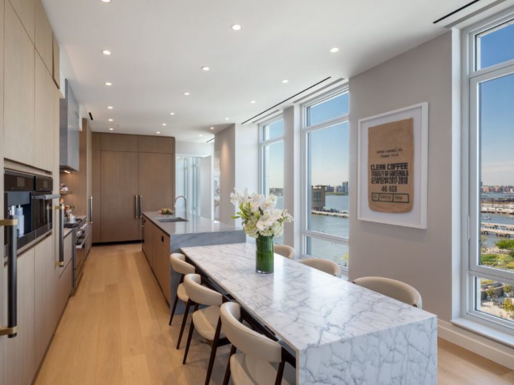 Interior view of 70 Vestry residence kitchen with window view of New York City. Has wood floors and marble counters.