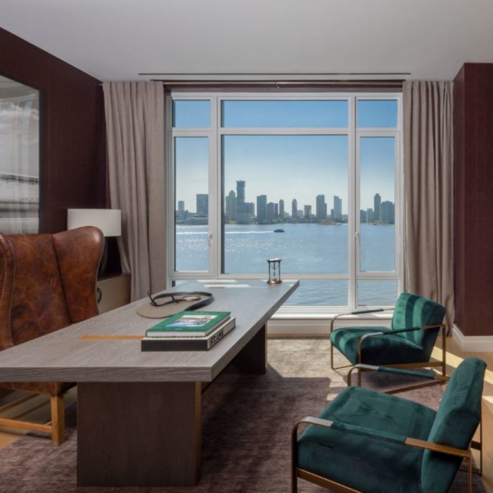 Interior view of 70 Vestry residence study with window view of New York City and waterfront. Has large desk and chairs.