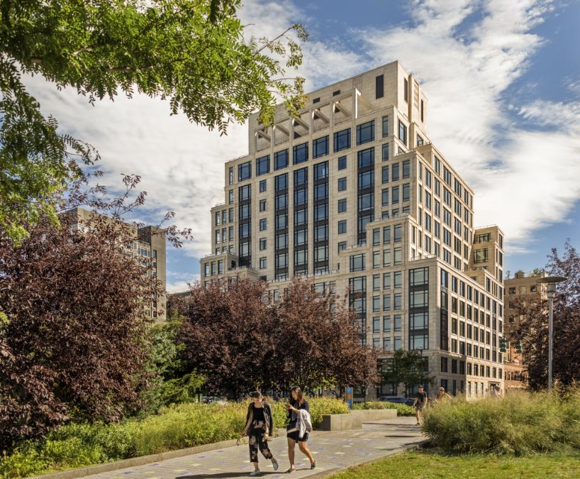 Exterior view of 70 Vestry condominiums in New York City. Has people running on a pathway with trees in the background.