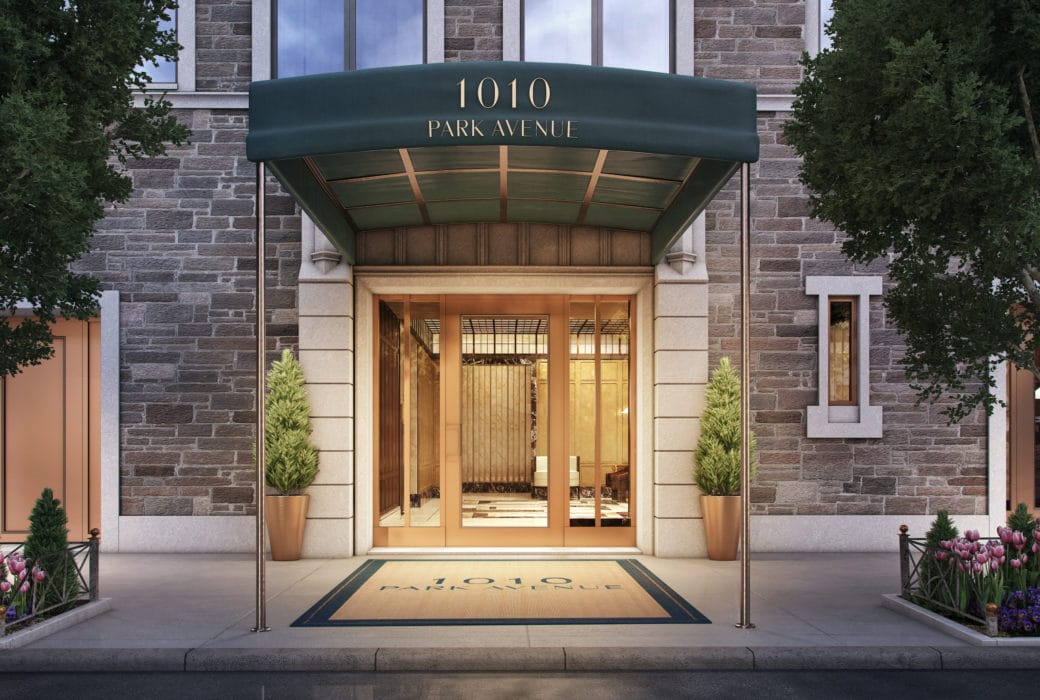 1010 Park Avenue Building Entry New York City. Front Doors of Brick Building with Canopy and Potted Trees Framing the Door.