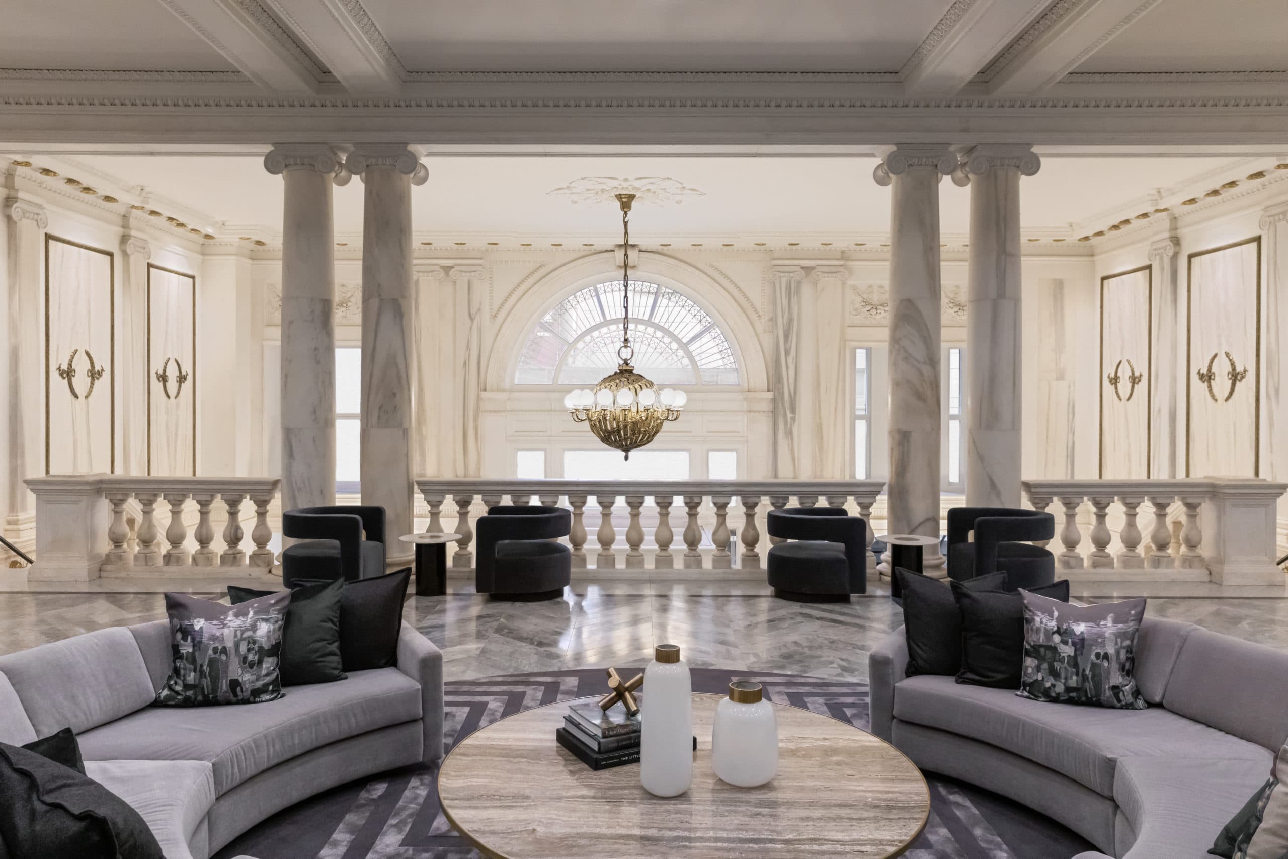 Interior modern sitting area inside 108 Leonard in NYC. It is decorated with marble columns and white and black furniture.
