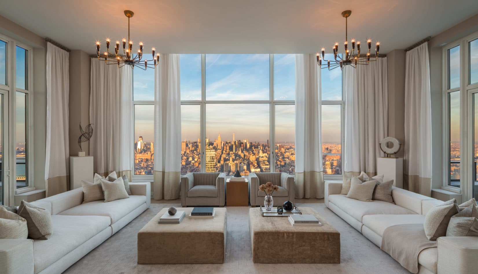 Interior view of living room inside 30 Park Place condominiums with window view of NYC. Has white walls and wood tables.