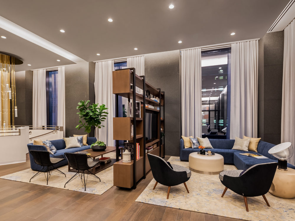 Interior view of 277 Fifth Avenue residence longue with blue chairs and couches. Includes wooden bookcase in NYC.