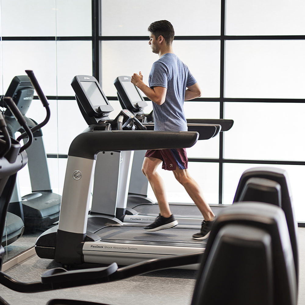 Fitness center at The Bryant condos in New York City. A man running on a treadmill with other empty treadmills around him.