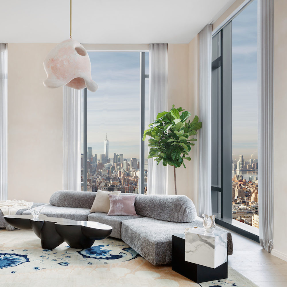 Interior view of living room in 277 Fifth Avenue condominiums with window views of NYC. Has chairs, couch, and lamp.