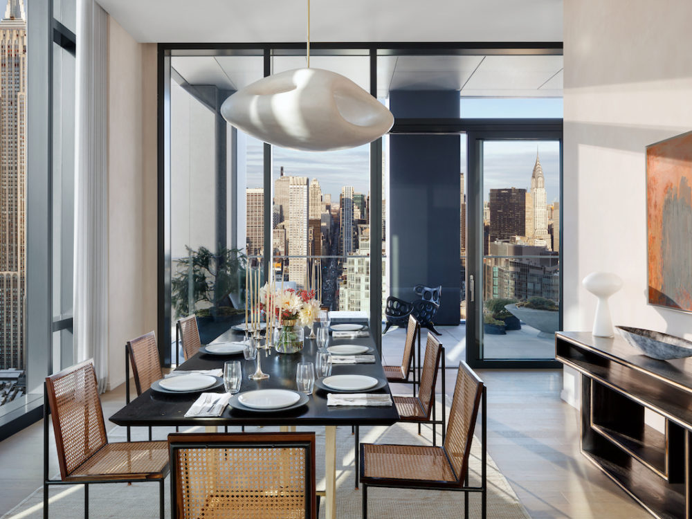 Interior view of 277 Fifth Avenue residence dining room with skyline view of NYC. Includes black table and brown chairs.