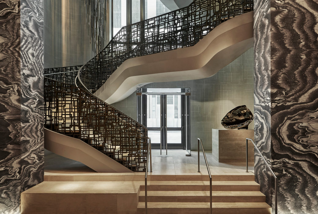 Interior view of 30 Park Place residence lobby in NYC. Includes view of wooden staircase with black rails leading upwards.