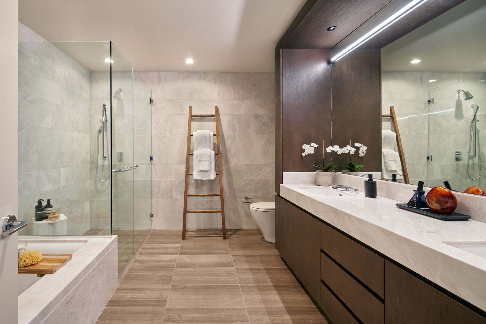 Master bathroom at The Avery condos in San Francisco. White marble double vanity with mirror, a soaking tub and full shower.