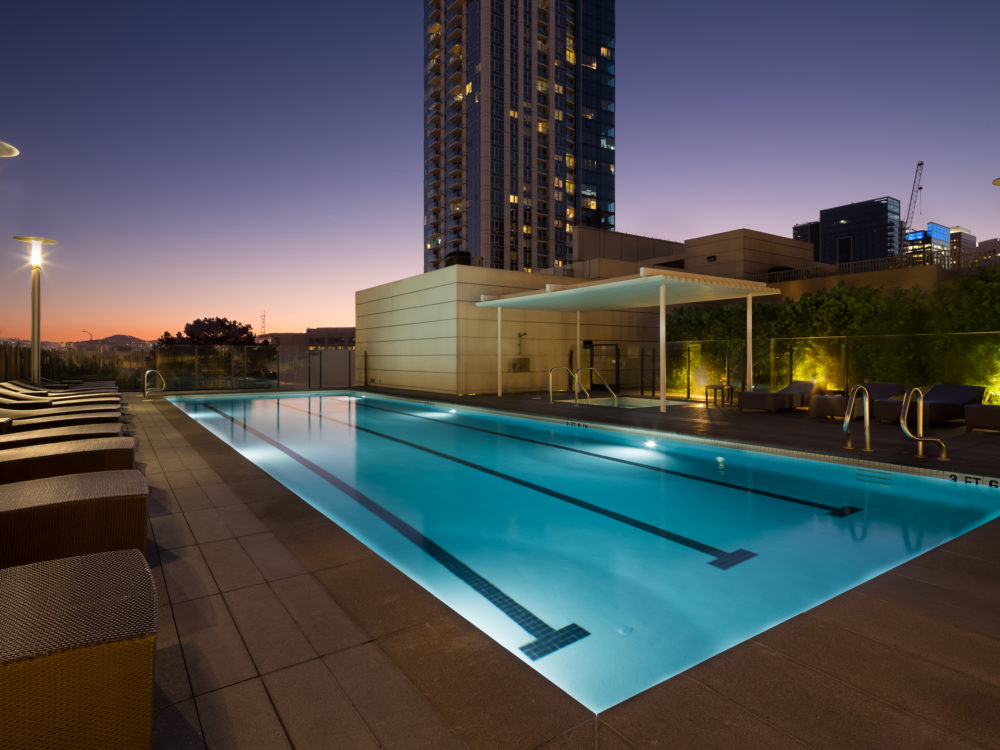 Pool terrace at The Harrison in San Francisco. Lit lap pool at night with umbrella stands and lined with lounge chairs.