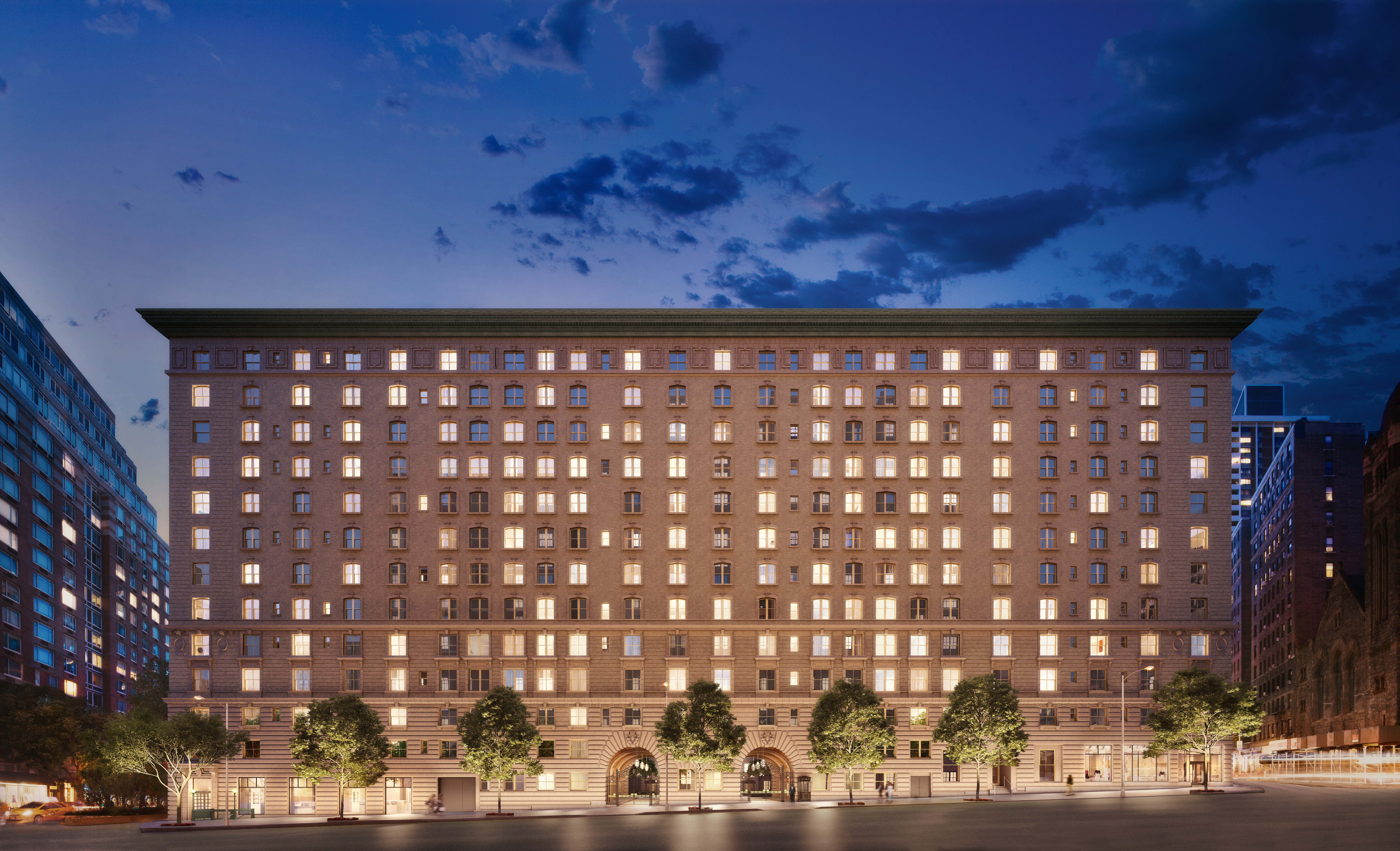 Exterior view of The Belnord apartments in New York. Large brick apartment building with lights in the windows at night.