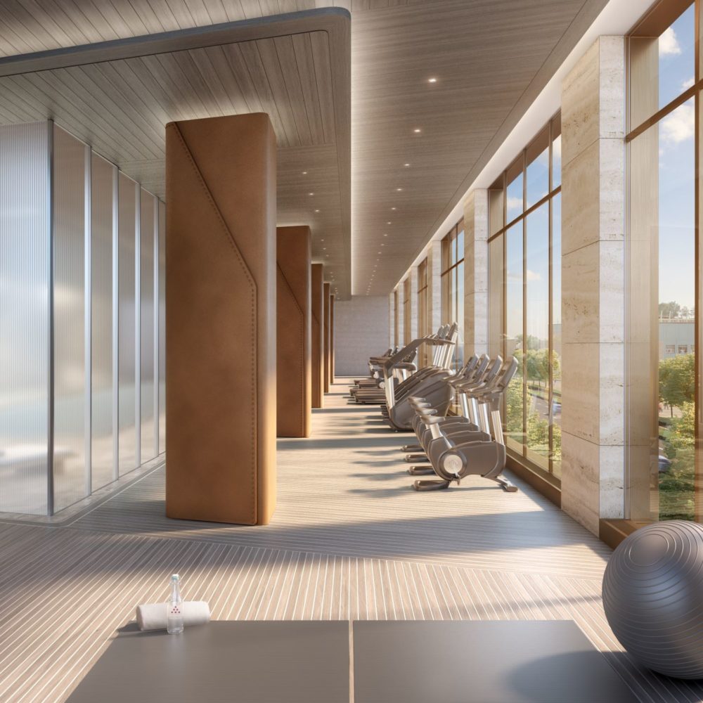 Fitness center at The Xi condos in New York. Long room with glass walls featuring treadmills, ellipticals and row machines.