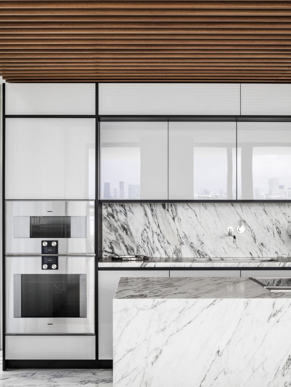 Kitchen at Monad Terrace luxury condominiums in Miami. Stone island and backsplash with white cabinets and appliances.