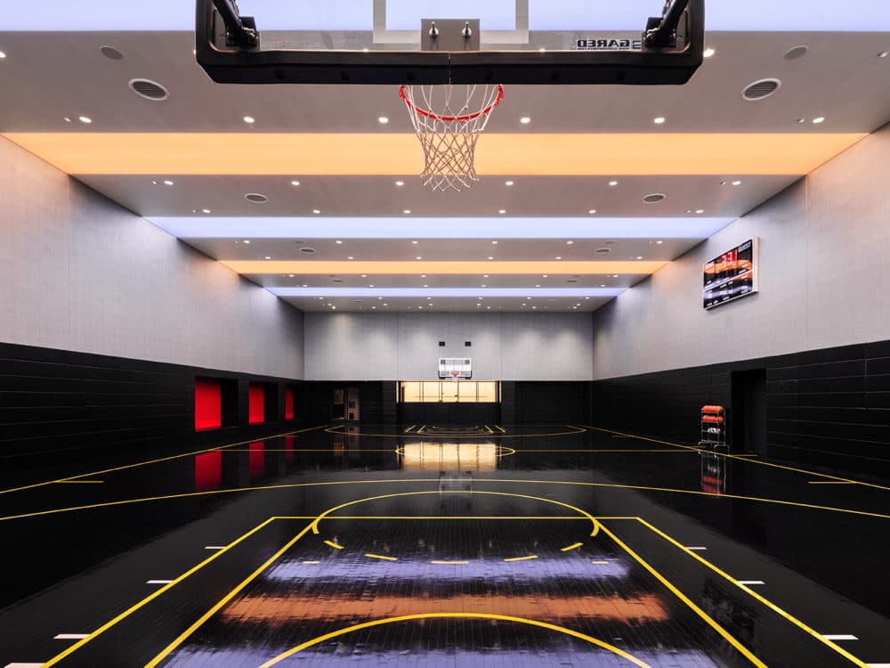 Full sized basketball court at One Manhattan Square condos in New York City. Black court with two hoops and scoreboard.