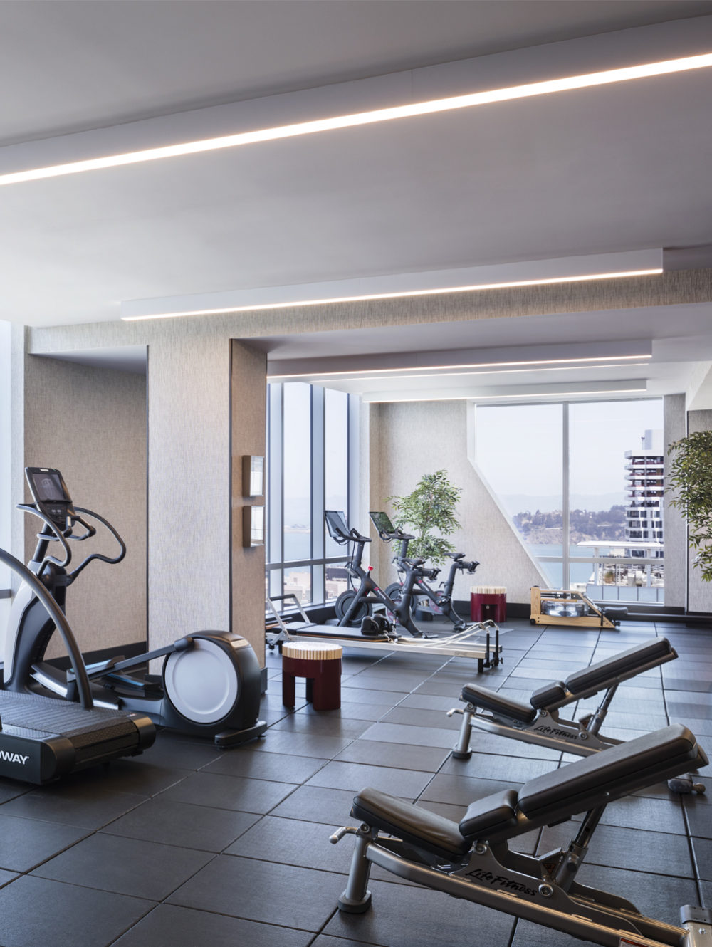 Gym at The Avery luxury condos in San Francisco. Oversized windows lined with treadmills & ellipticals providing city views.