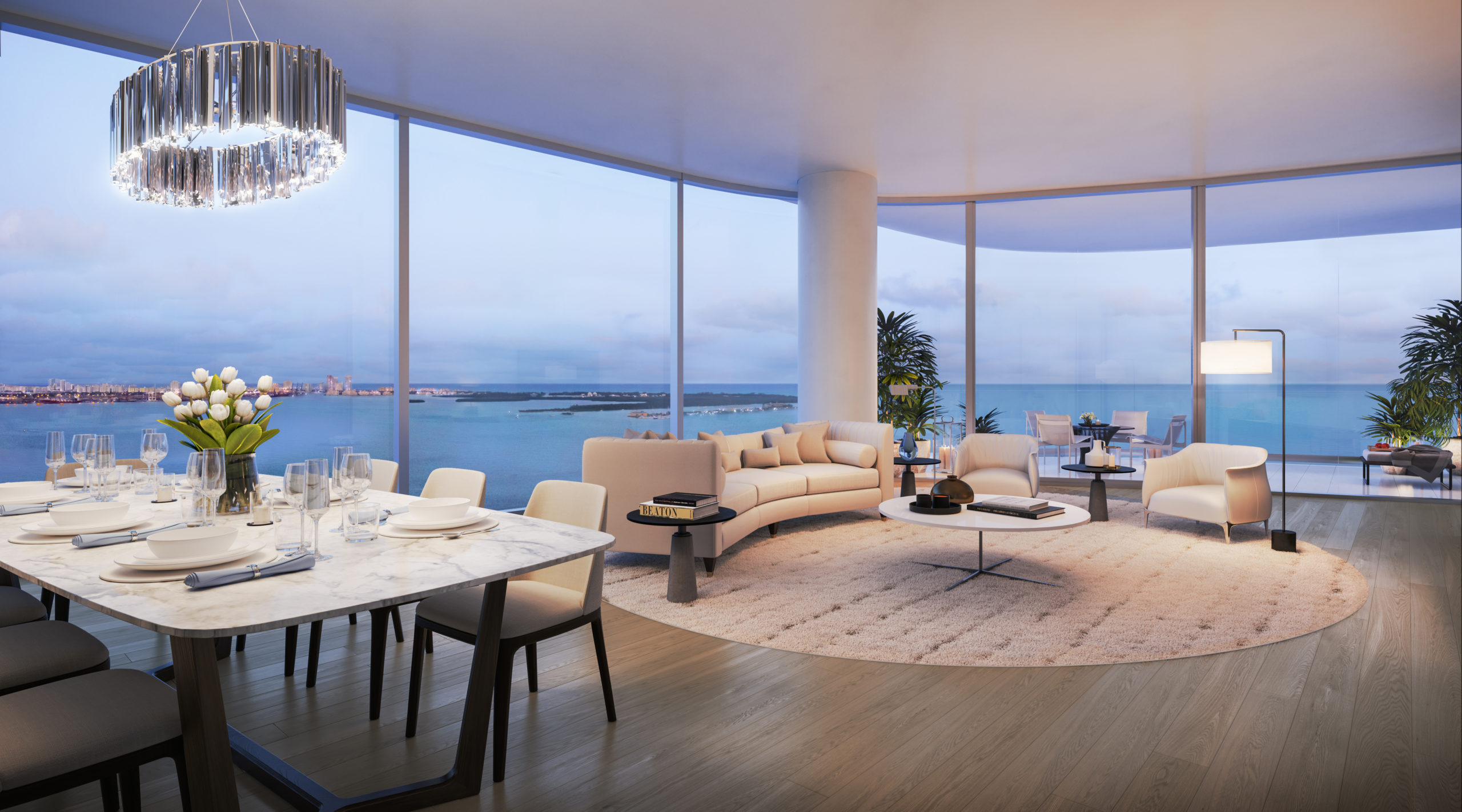 Condo living room at Una Residences in Miami. Open room with dining table, a couch, coffee table, and clear views of the bay.