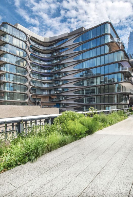 Ground view of 520 W 28 condominiums in New York City. Has a pathway leading into buildings with green shrubbery on side.
