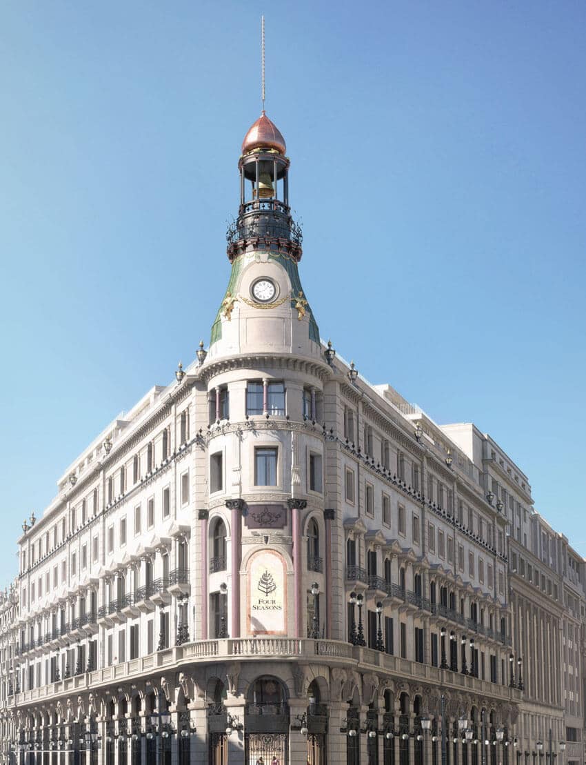 Exterior view of the Four Seasons Hotel at Canalejas in Madrid. White stone building with columns bordering the building.