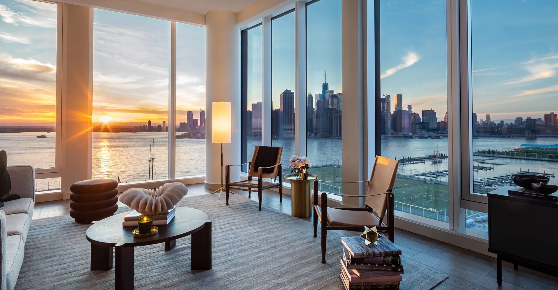 Interior view from Quay Tower luxury condos in Brooklyn, NY. Corner living room with tall windows and city views.