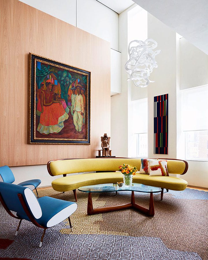 Interior living space of Park Avenue Triplex designed by Amy Lau. High ceilings, a brown accent wall, and two couches.