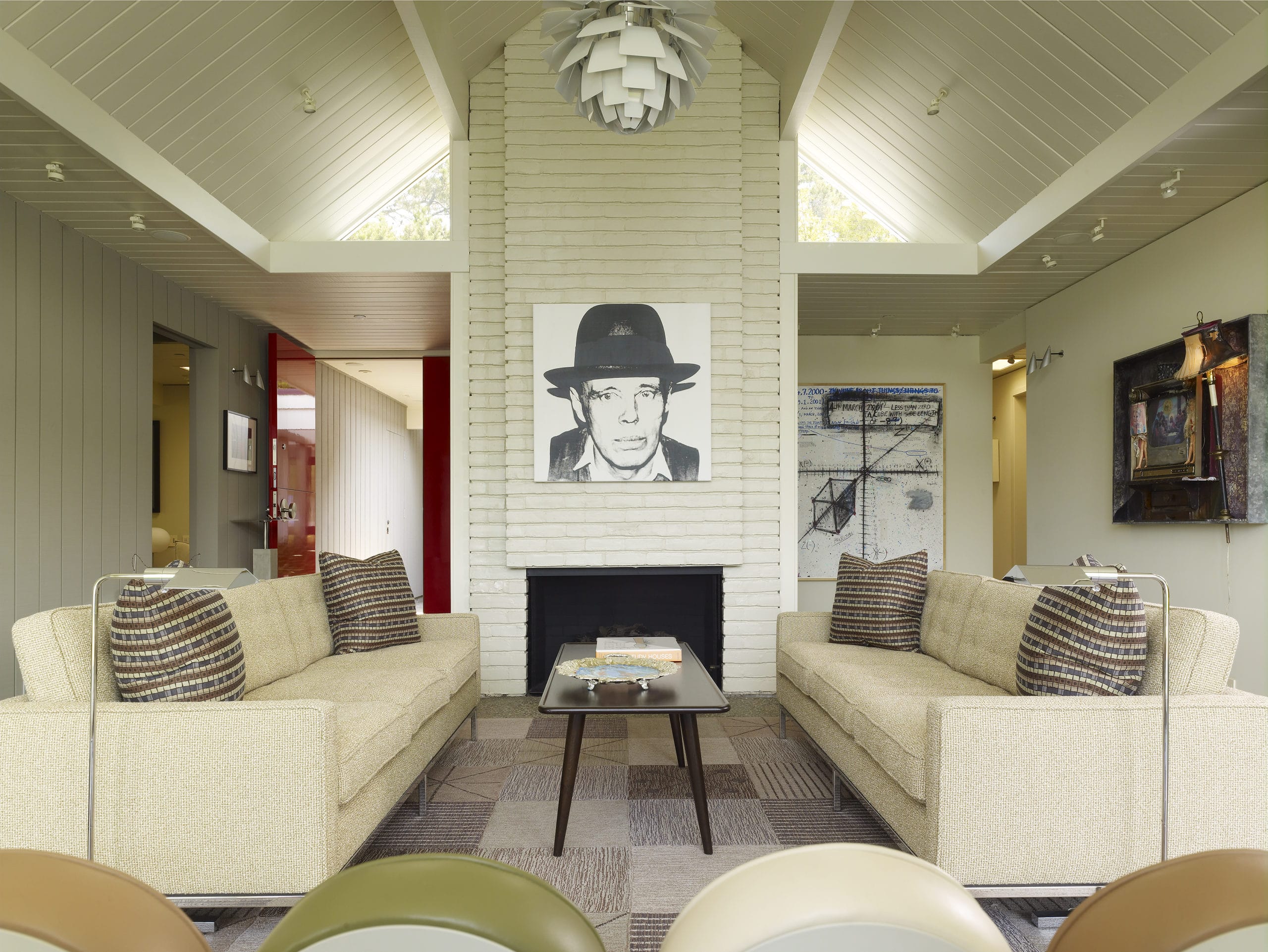 Living room with gray-stained wood walls, a brick fire place with a black and white picture hanging and two couches.