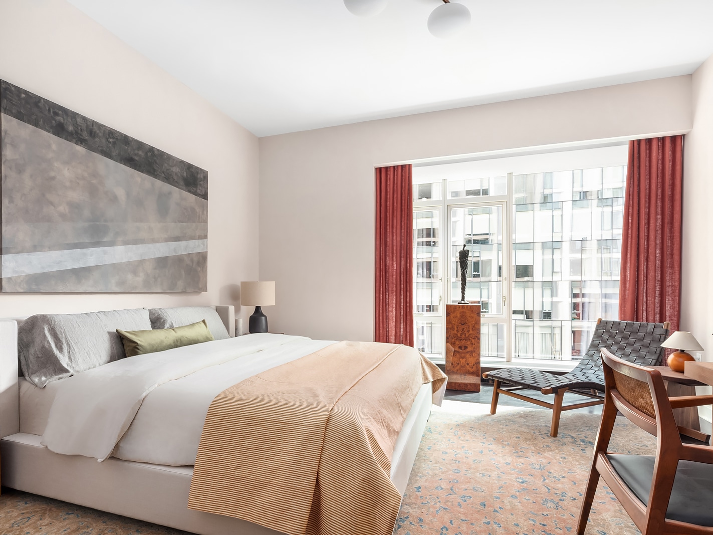 Bedroom at The Hayworth in New York. Large windows providing natural light and views with a large bed and marble art piece.