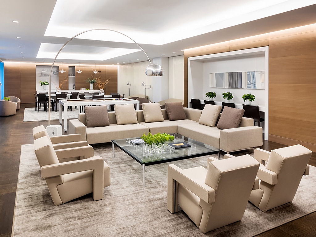 Community lounge at The Hayworth condominiums in New York. Communal room with a tan couch & chairs and a large dining table.