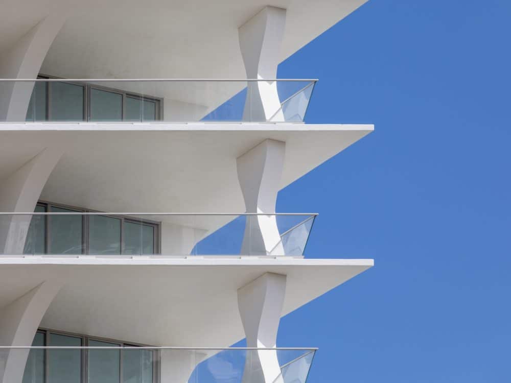 Exterior close up view of Jade Signature condominiums balcony with oceanfront view. Has a white, triangular deck with rails.